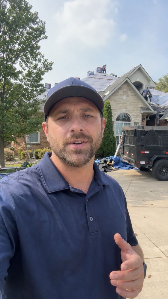 Raw, unedited phone video frame of a roofing crew lead giving a project check-in in front of a job in progress.